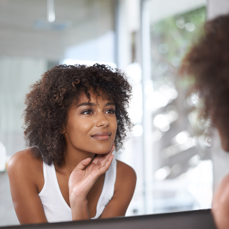 Mulher no espelho com pontos escuros