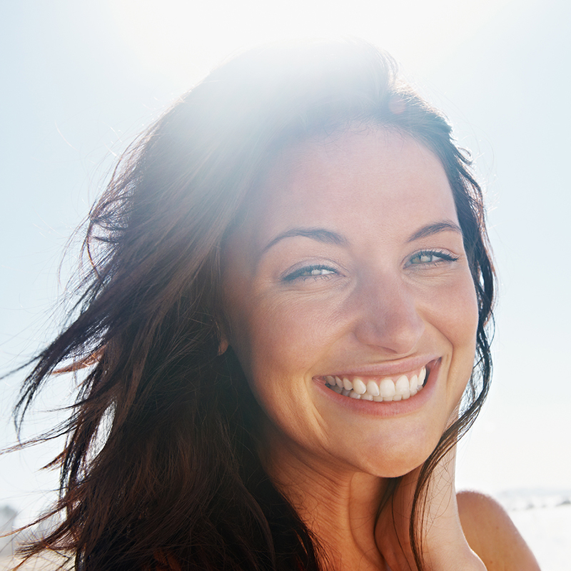 Mulher a sorrir com o sol ao fundo