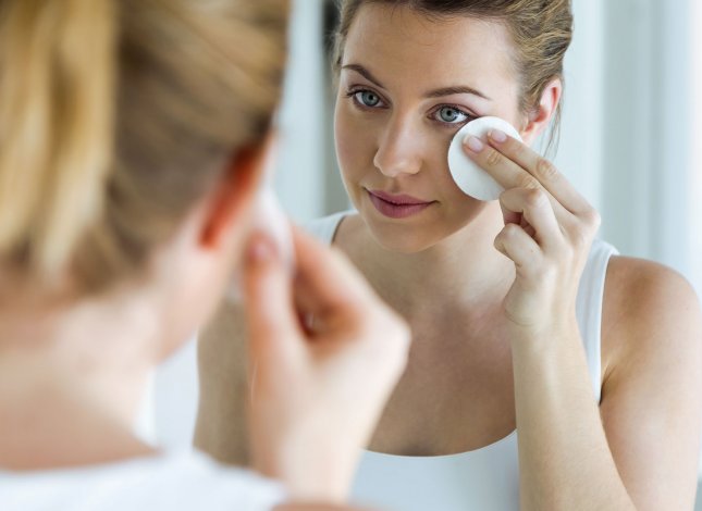 Mulher a limpar o rosto com um disco de algodão
