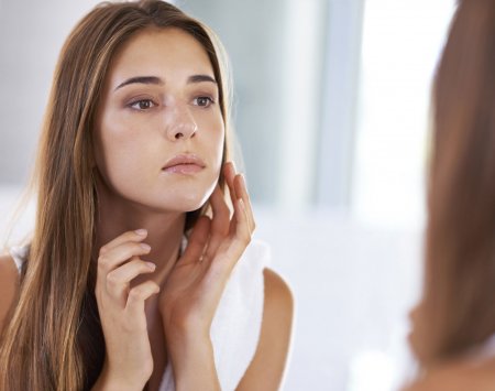 Woman checking her skin in a mirror